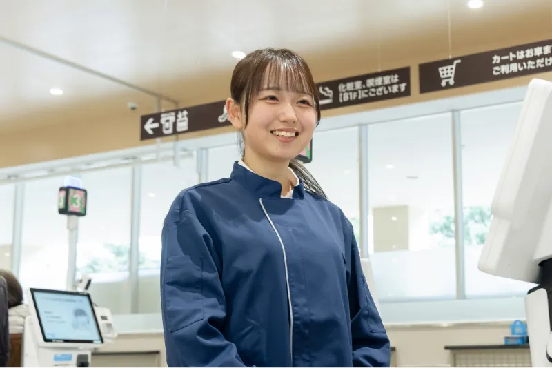 現場の制服姿でレジに立ち、笑顔でお客様を迎え入れるK.Y.さんの様子