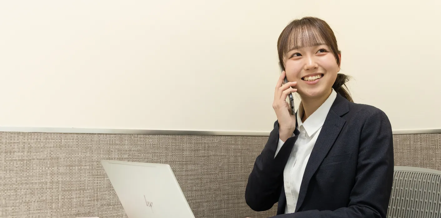 スーツ姿のK.Y.さんが、会議室で電話をしている様子