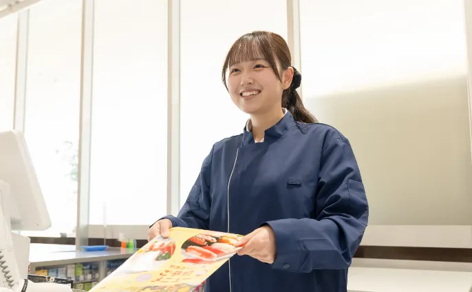 従業員がサービスカウンターで冊子を見せながら、笑顔でお客様にご案内をしている様子