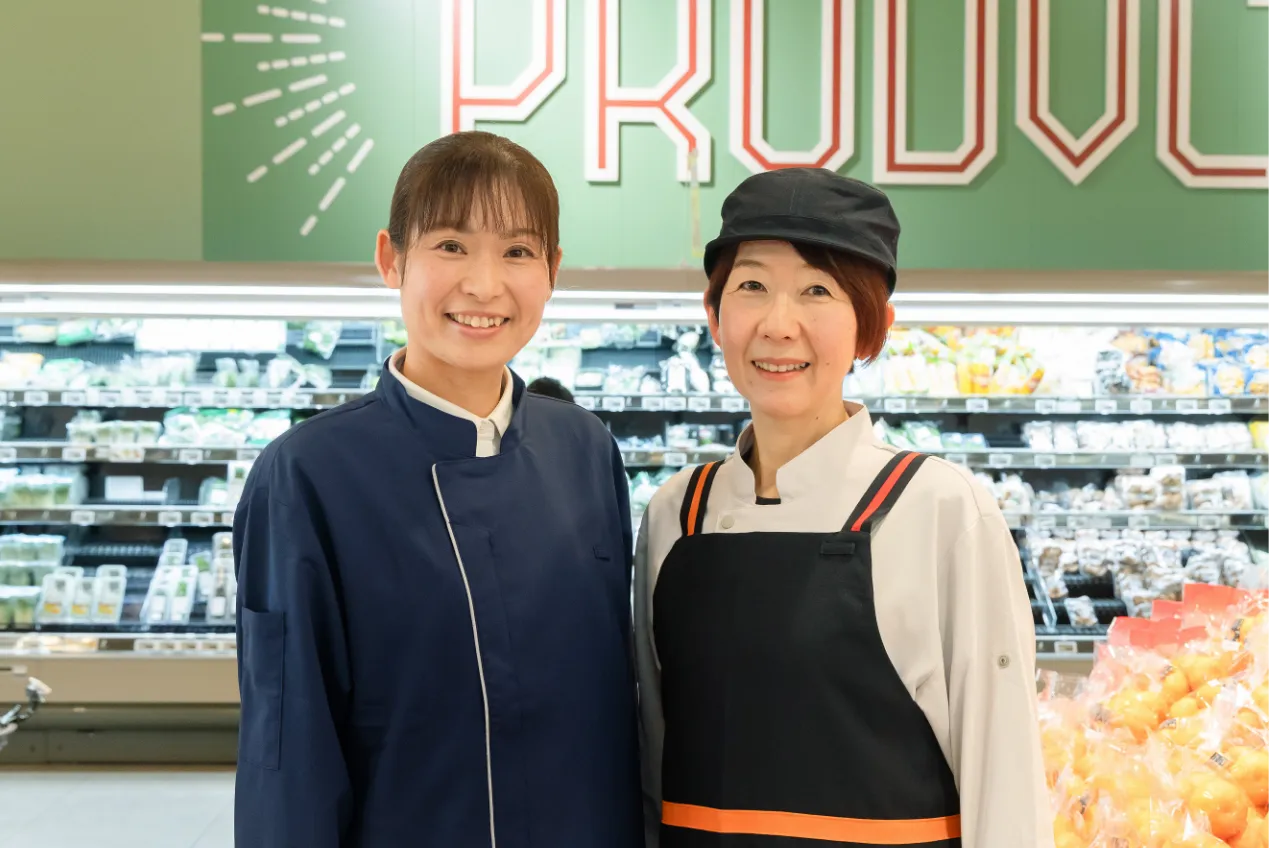 従業員二人が、笑顔で正面を向いて立っている様子