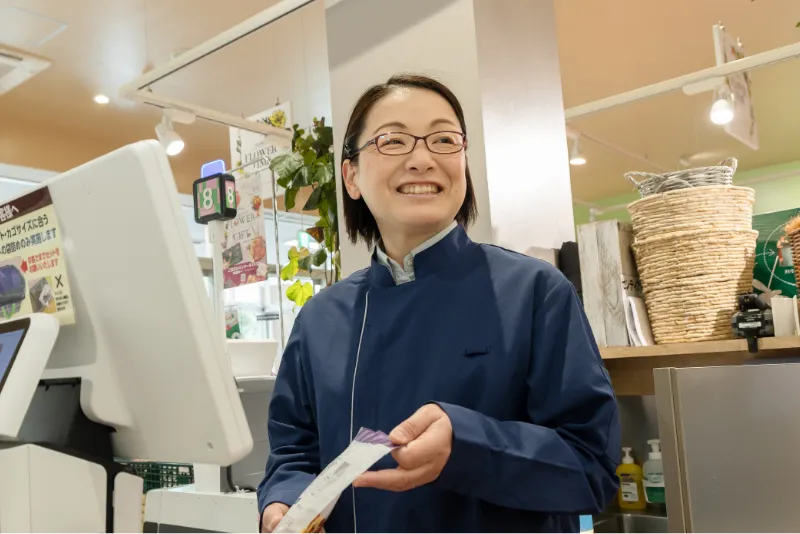 K.Y.さんが商品をレジに通しながらお客様へ笑顔を向けている様子