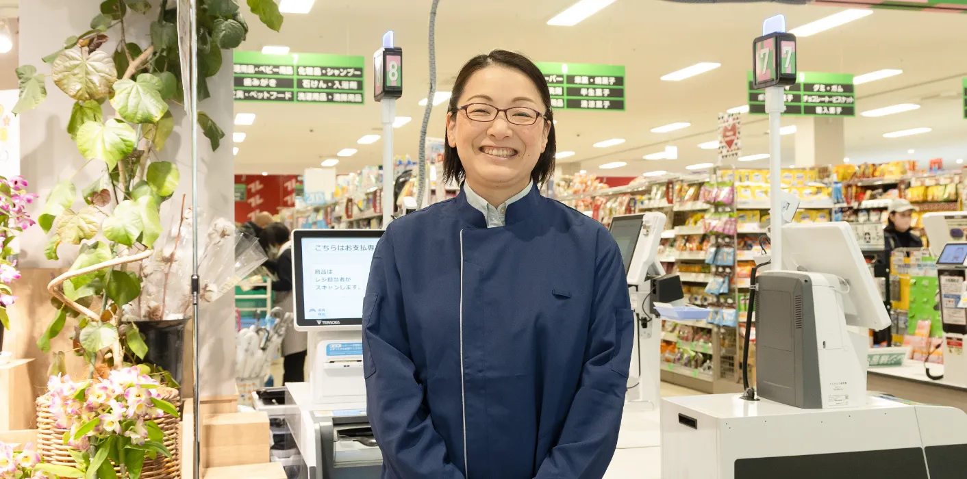 K.Y.さんがレジを背にして笑顔で立っている様子