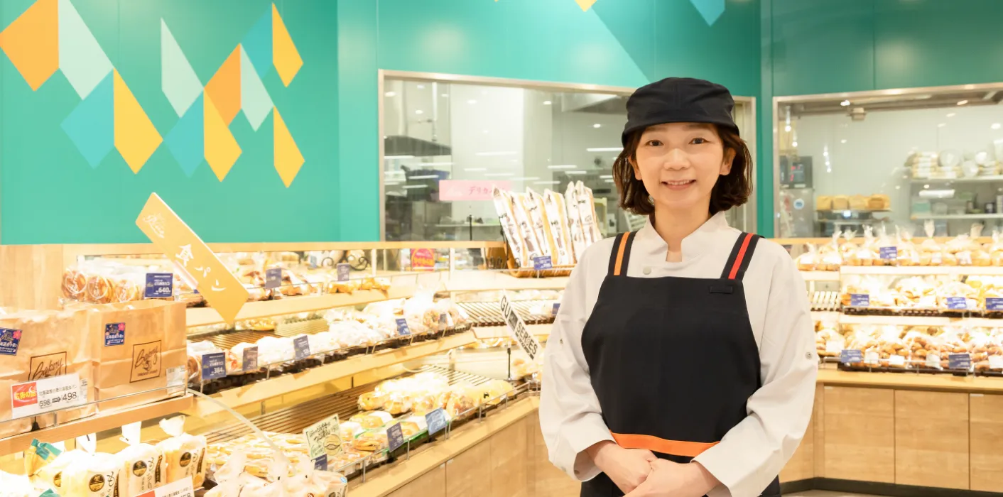 H.T.さんがベーカリーコーナーを背にして笑顔で立っている様子