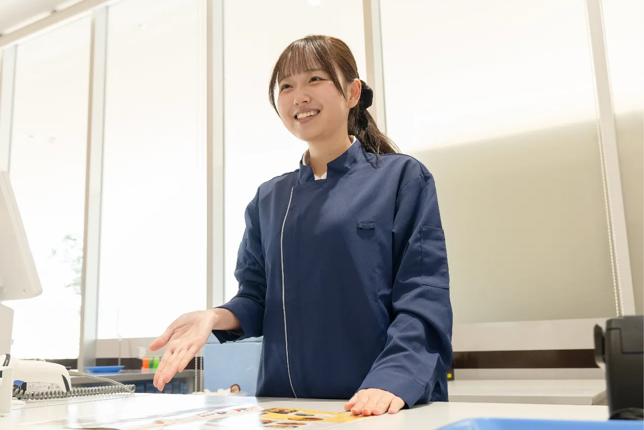 カウンターでパンフレットを指さし、お客様へご案内している様子